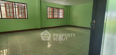 Spacious empty room with green walls and tiled floor, featuring large windows for natural light.