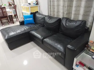 Spacious living room with elegant black leather sectional sofa and modern decor.