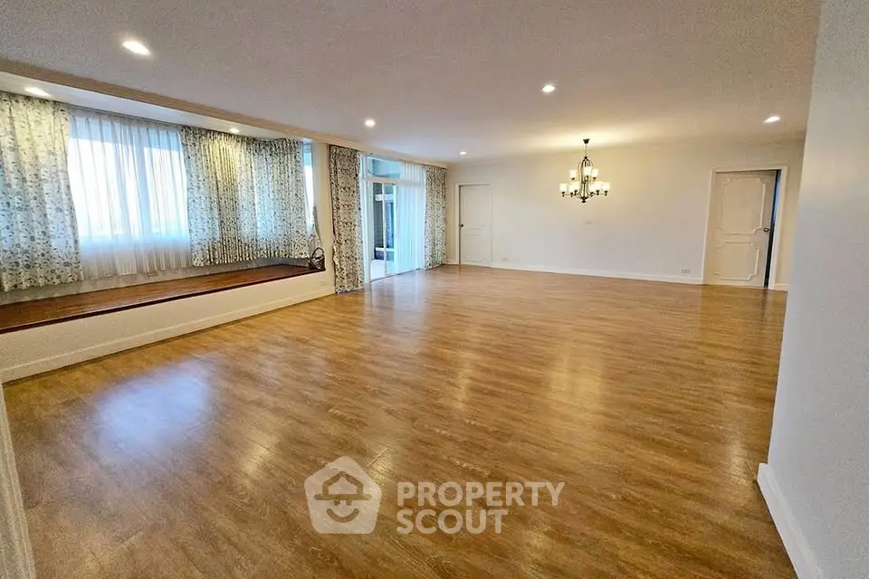 Spacious empty living room with wooden flooring and elegant chandelier