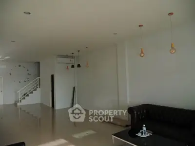 Spacious modern living room with elegant lighting and sleek black sofa, perfect for stylish urban living.
