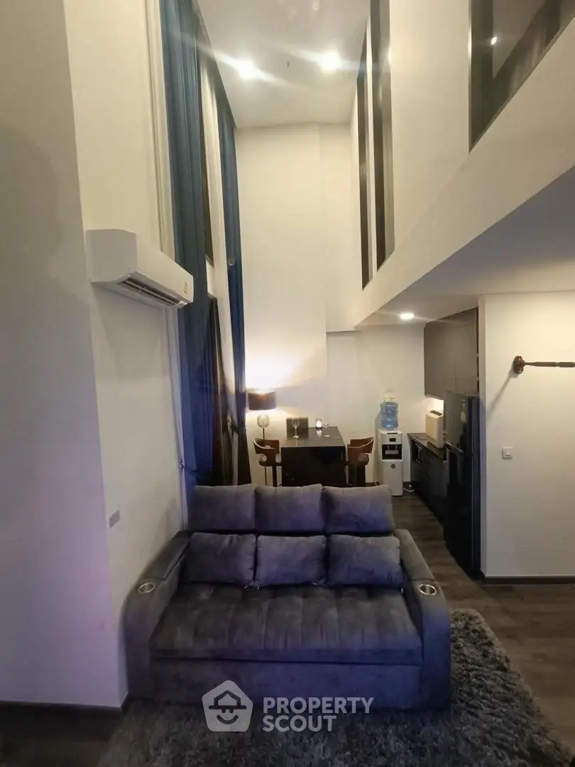 Modern loft-style living room with high ceilings and cozy seating area.