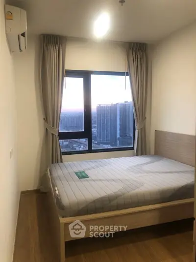 Modern bedroom with large window offering stunning city views, featuring a comfortable bed and elegant curtains.
