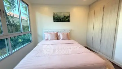 Cozy bedroom with large window and built-in wardrobe, featuring a serene forest painting.