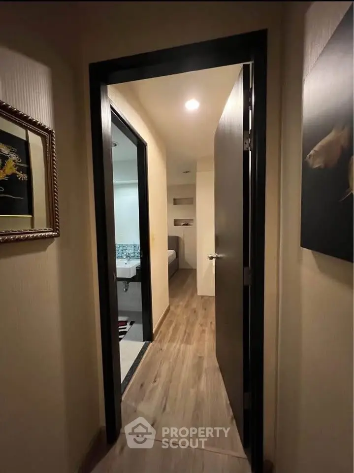 Cozy hallway leading to a modern bathroom with wooden flooring and elegant decor.