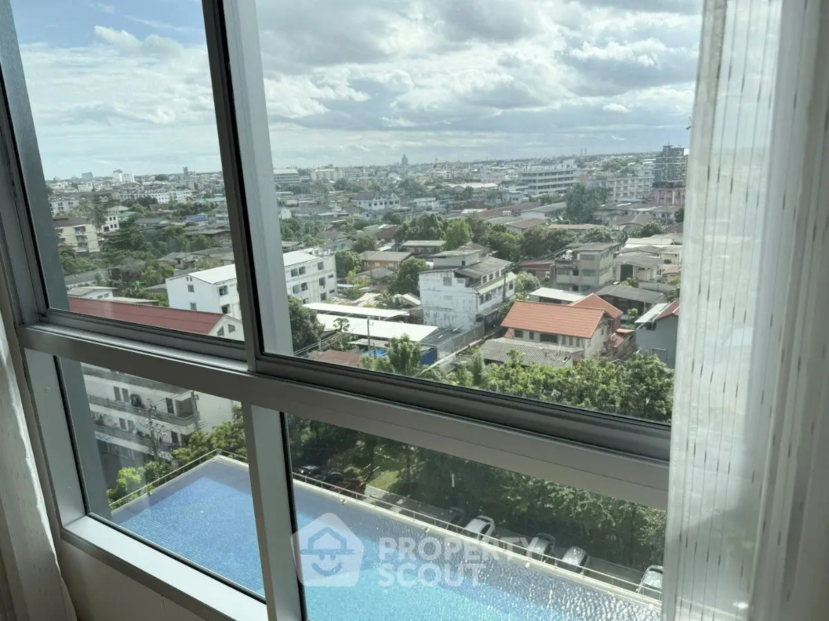Stunning cityscape view from high-rise window overlooking pool and urban landscape.