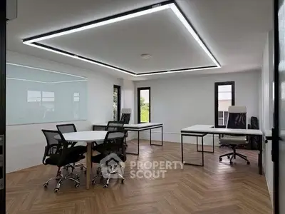 Modern office space with sleek design and natural light, featuring stylish furniture and wood flooring.