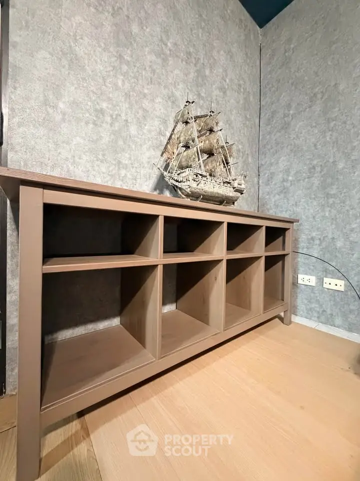 Stylish wooden storage unit with decorative ship model in modern interior setting.