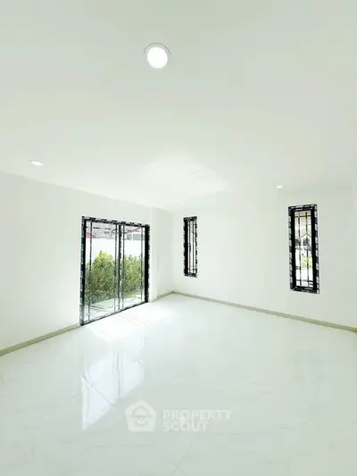 Spacious and bright living room with large windows and modern white flooring.