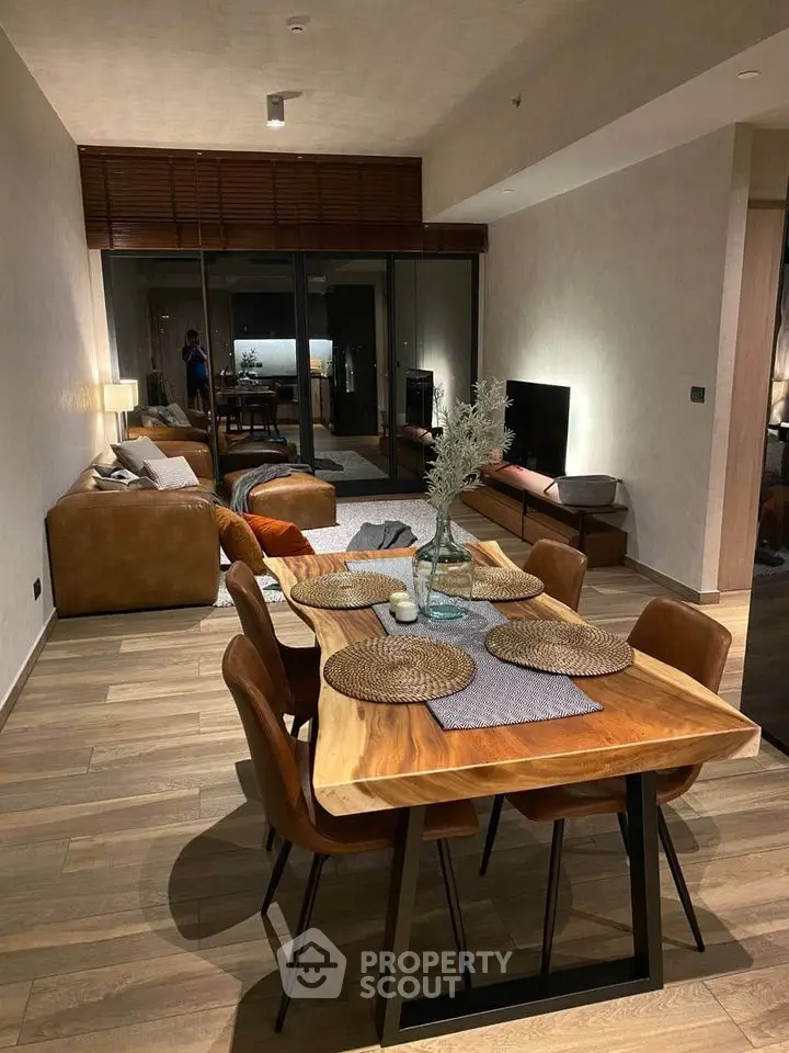 Modern open-plan living room with stylish dining area and cozy seating, featuring wooden flooring and contemporary decor.