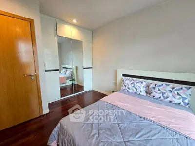 Cozy bedroom with mirrored wardrobe and stylish bedding in modern apartment.