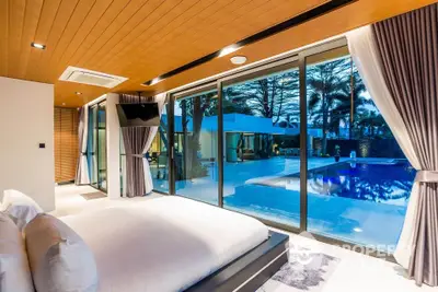 Luxurious bedroom with pool view and modern decor in a stunning real estate property.