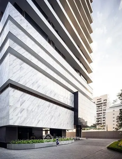 Modern high-rise building with sleek marble facade and spacious entrance in urban setting.