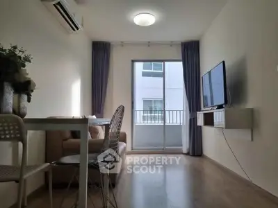 Modern living room with sleek furniture and natural light, featuring a wall-mounted TV and balcony access.