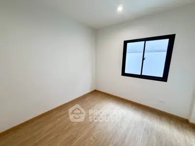 Spacious empty room with wooden flooring and large window, perfect for customization.