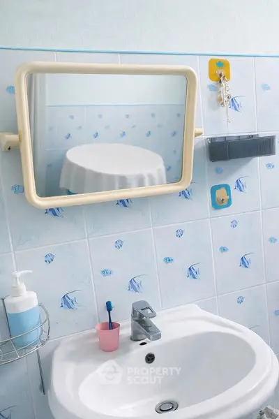 Charming bathroom with fish-themed tiles and modern sink, perfect for a cozy home.