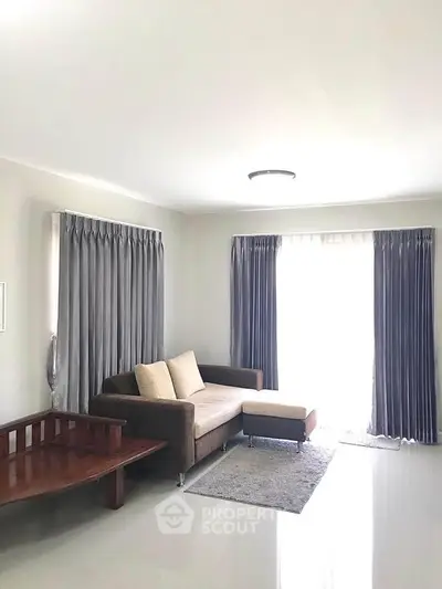 Spacious living room with modern sofa and elegant curtains, perfect for relaxation and entertaining.