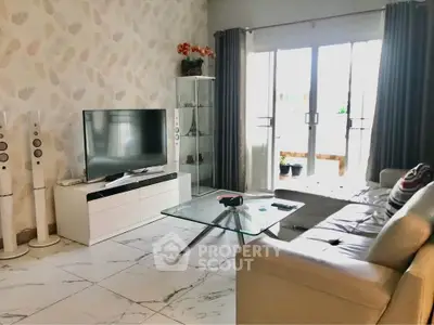 Stylish living room with modern decor, large TV, and glass coffee table.