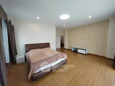 Spacious bedroom with modern decor and wooden flooring