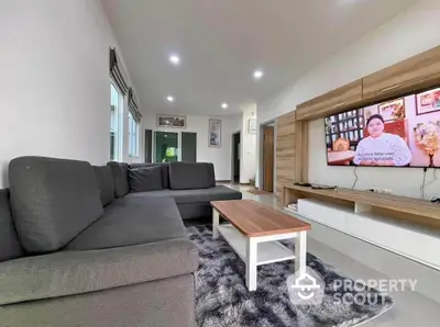 Spacious living room with modern gray sofa and wall-mounted TV