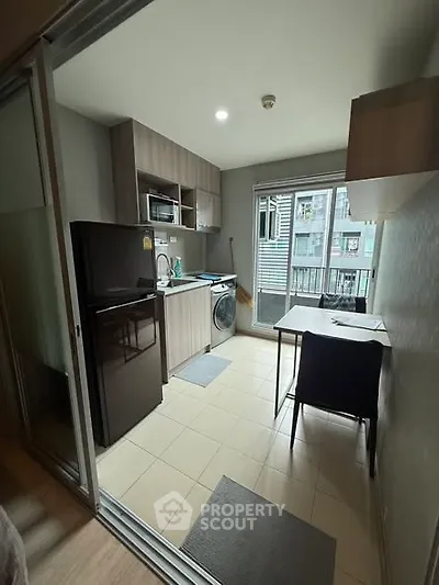 Modern kitchen with appliances and dining area in a compact apartment setting.