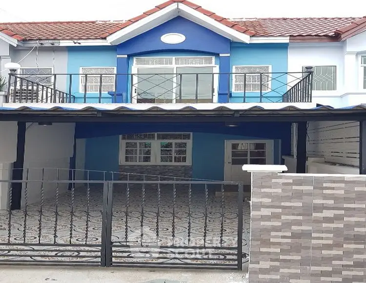 Charming blue townhouse with decorative iron gate and spacious driveway.