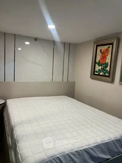 Cozy bedroom with modern decor and elegant wall art, perfect for relaxation.