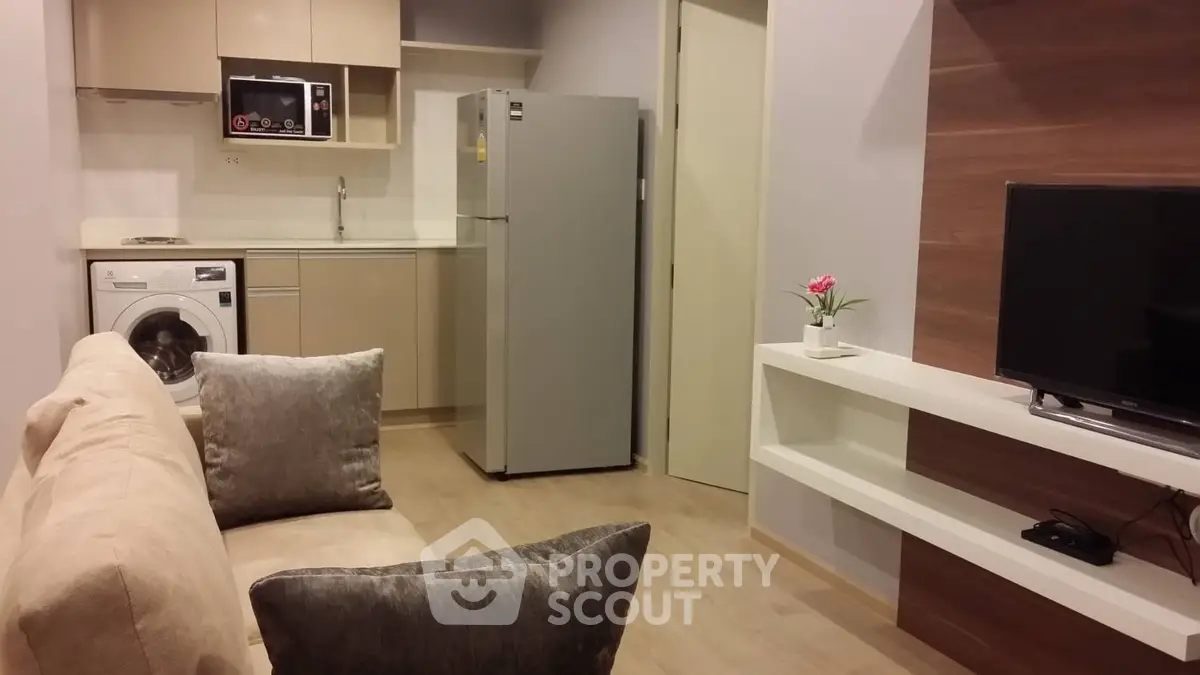 Modern apartment living room with open kitchen, featuring washing machine and sleek appliances.