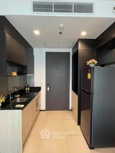 Modern kitchen with sleek black appliances and stylish cabinetry in a contemporary apartment.