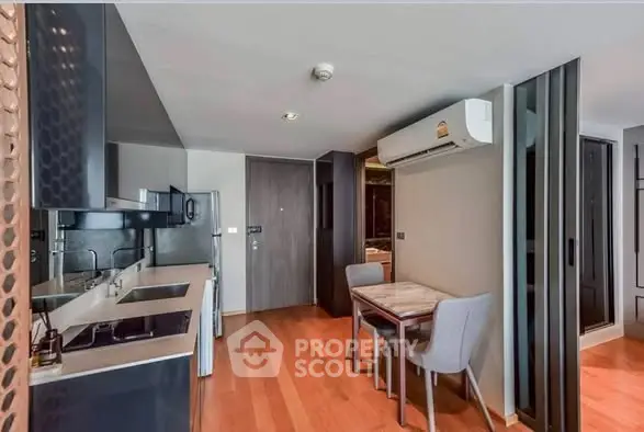 Modern kitchen and dining area with sleek design and wooden flooring in a stylish apartment.