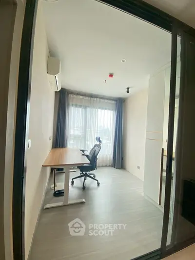 Modern study room with large window and ergonomic chair in a bright apartment.