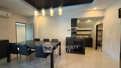 Modern dining area with sleek black furniture and open kitchen layout