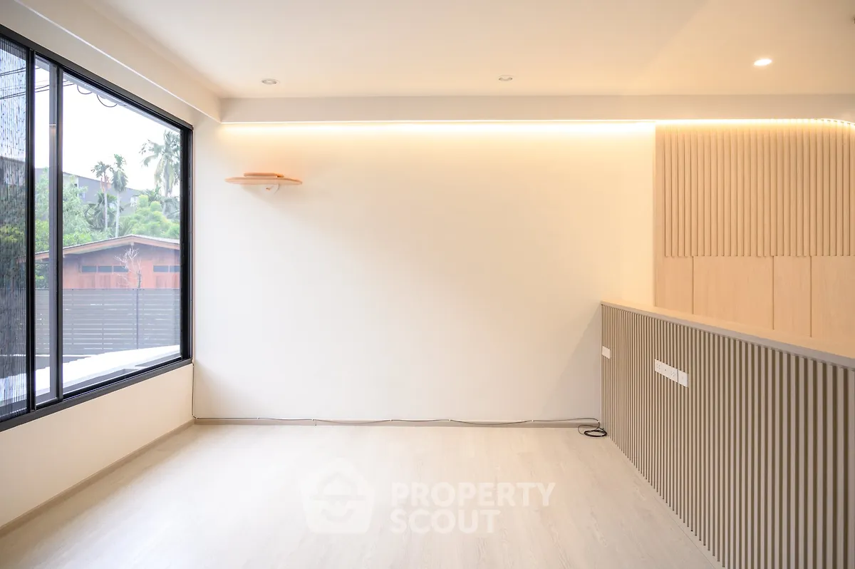 Modern minimalist living room with large window and wooden accents, offering a bright and airy atmosphere.