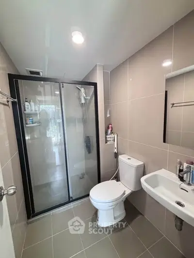 Modern bathroom with glass shower, sleek fixtures, and neutral tiles.
