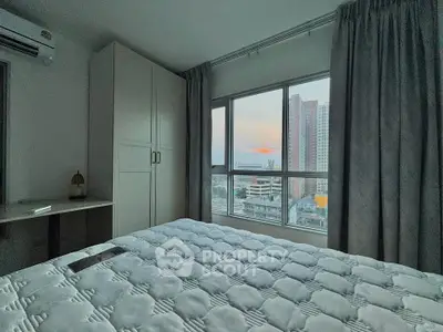 Cozy bedroom with large window offering stunning city views, featuring a comfortable bed and ample storage space.