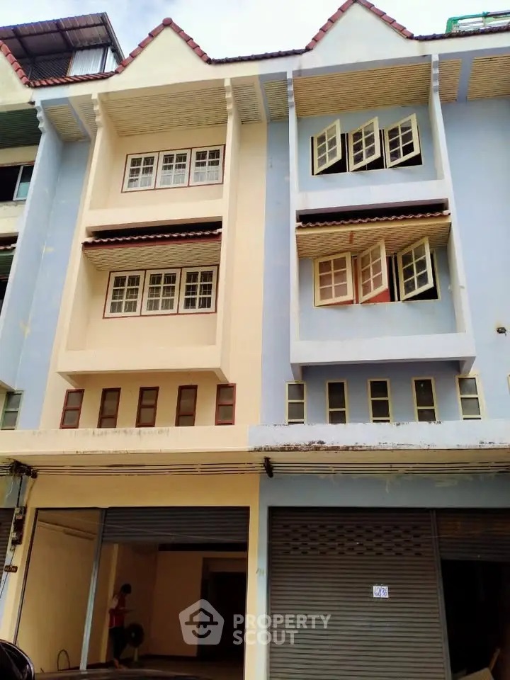 Charming multi-story building with unique window design and pastel facade, ideal for urban living.