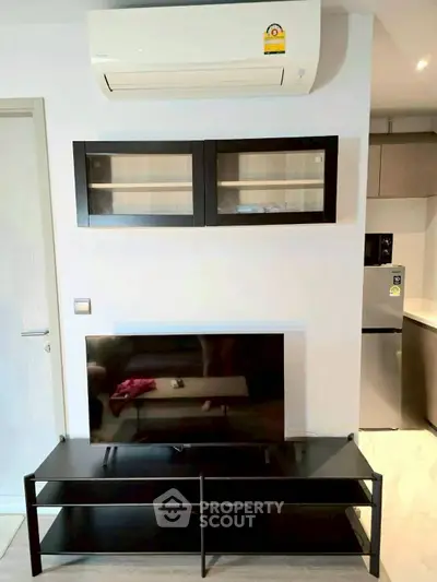 Modern living room with sleek TV stand and wall-mounted cabinets, featuring a compact air conditioning unit.
