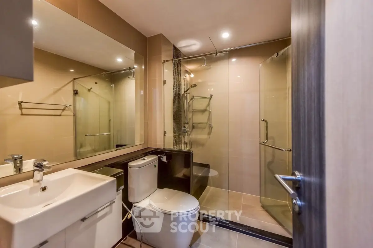 Modern bathroom with glass shower and sleek fixtures in contemporary apartment.