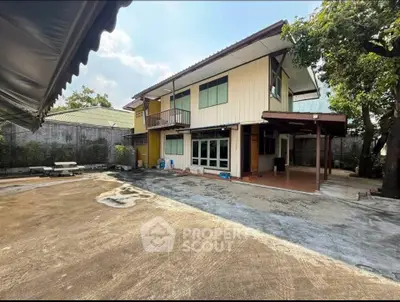 Spacious two-story house with large outdoor area and mature trees, perfect for family living.