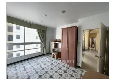 Spacious bedroom with large window and stylish tile flooring in modern apartment