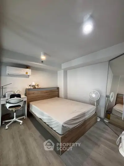 Modern bedroom with wooden bed, mirrored closet, and workspace in a cozy apartment.
