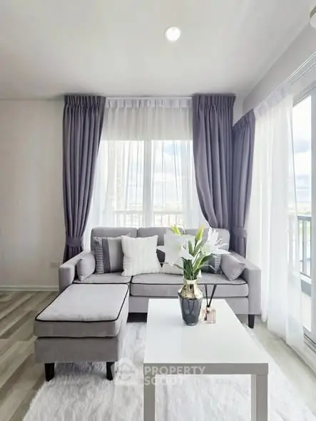 Bright and modern living room with elegant gray sofa and large windows.