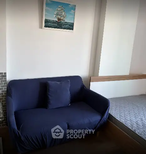 Cozy living area with a navy blue sofa and nautical wall art, perfect for relaxation.