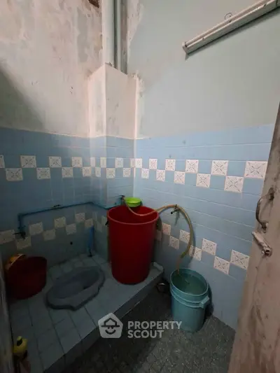Simple bathroom with blue tiles and basic amenities in a modest home.