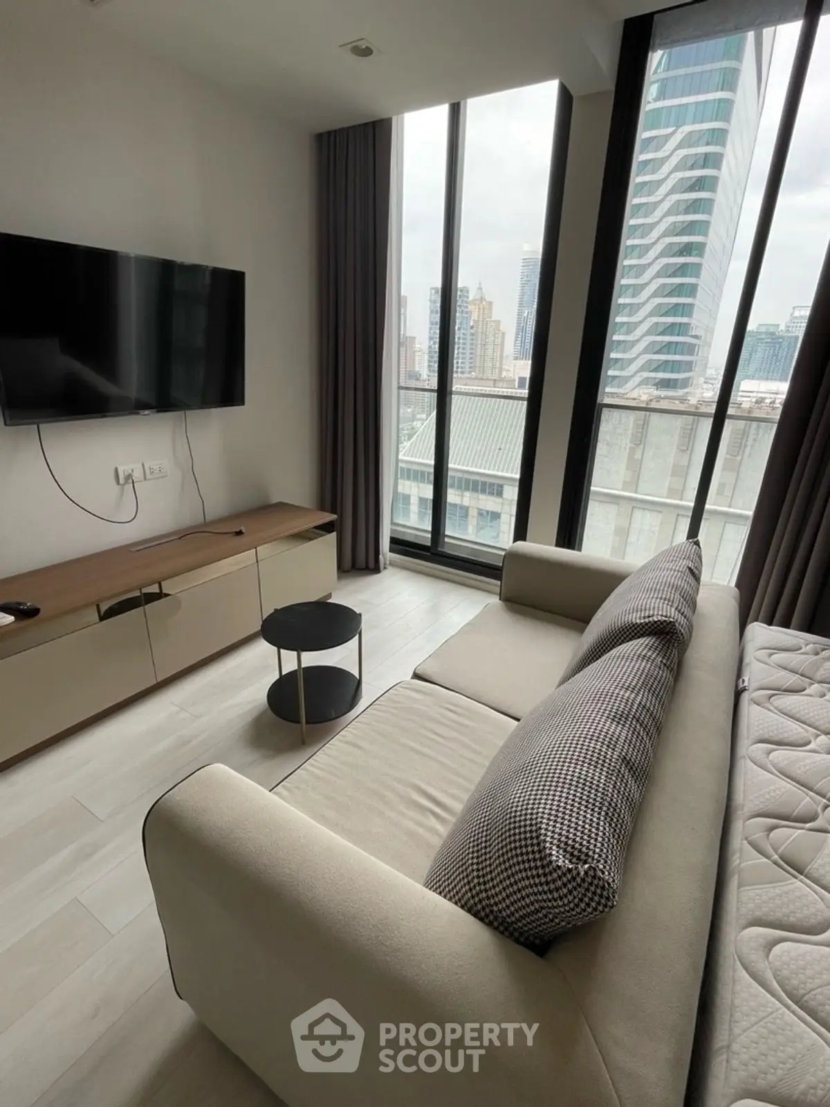 Modern living room with city view, sleek furniture, and large windows.