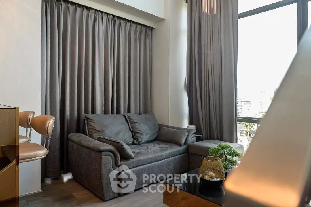 Modern living room with stylish sofa and large windows offering city views.