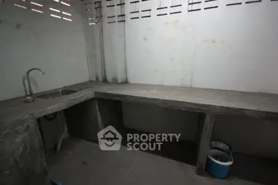 Minimalist concrete kitchen with sink and open storage space