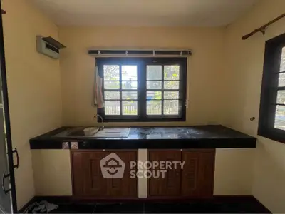 Charming kitchen with large windows and sleek countertops, perfect for culinary creativity.