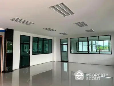 Spacious and well-lit commercial space with reflective flooring, large windows, and modern lighting fixtures, ideal for businesses seeking a professional environment.