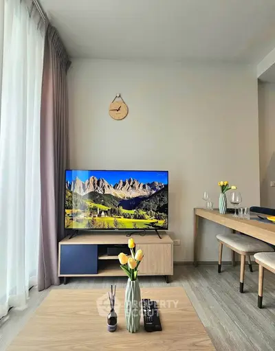 Modern living room with stylish decor, large TV, and natural light from floor-to-ceiling windows.