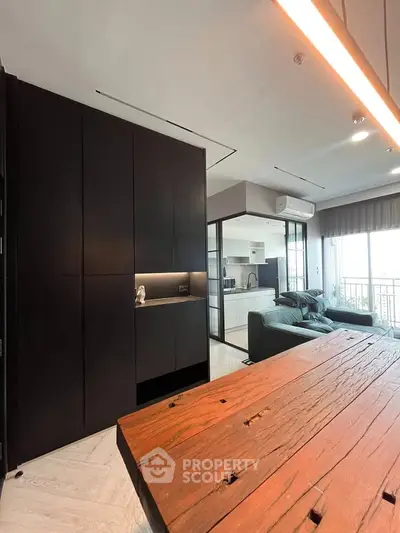 Modern open-plan living room with sleek kitchen and rustic wooden table, featuring a cozy balcony view.